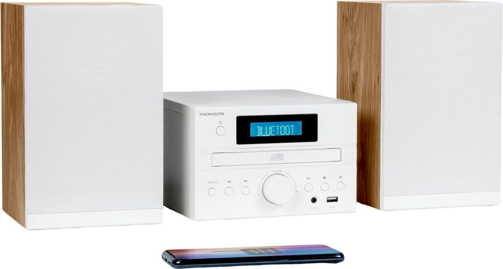 A white and wood-grain home sound system with two speakers and a central unit, placed on a white background. A smartphone is visible in the foreground.