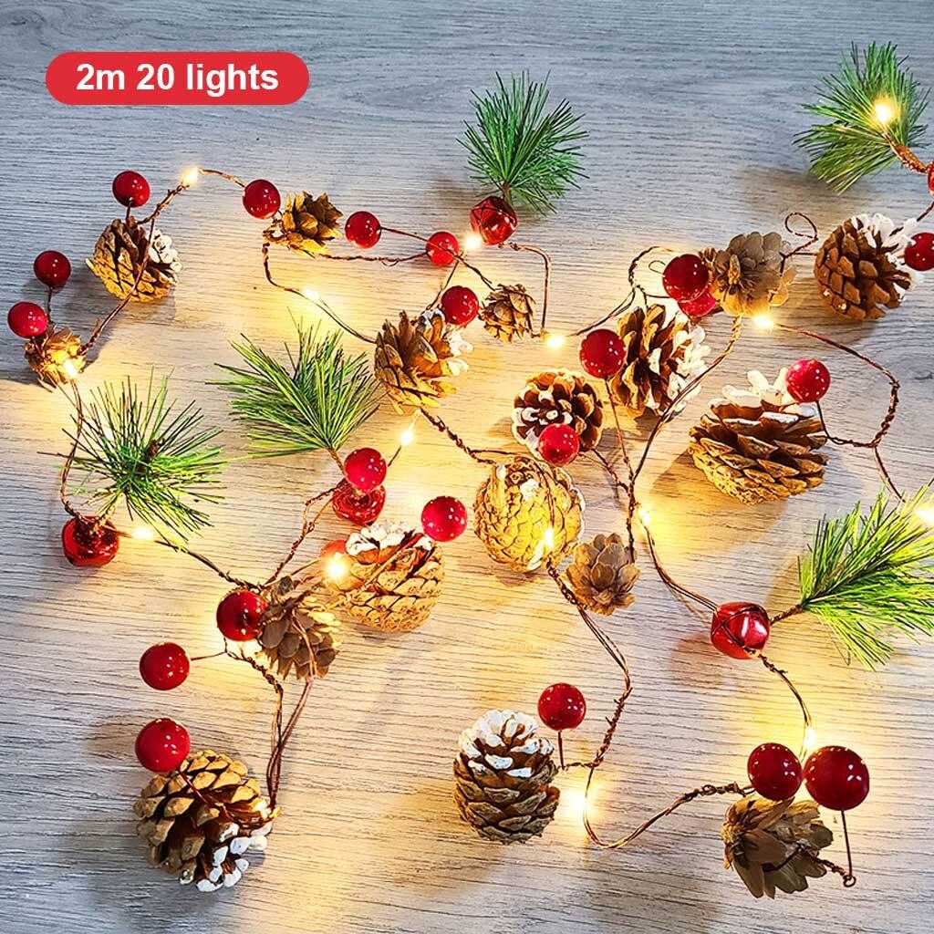 A string of Christmas lights decorated with pinecones, red berries, and pine needles.