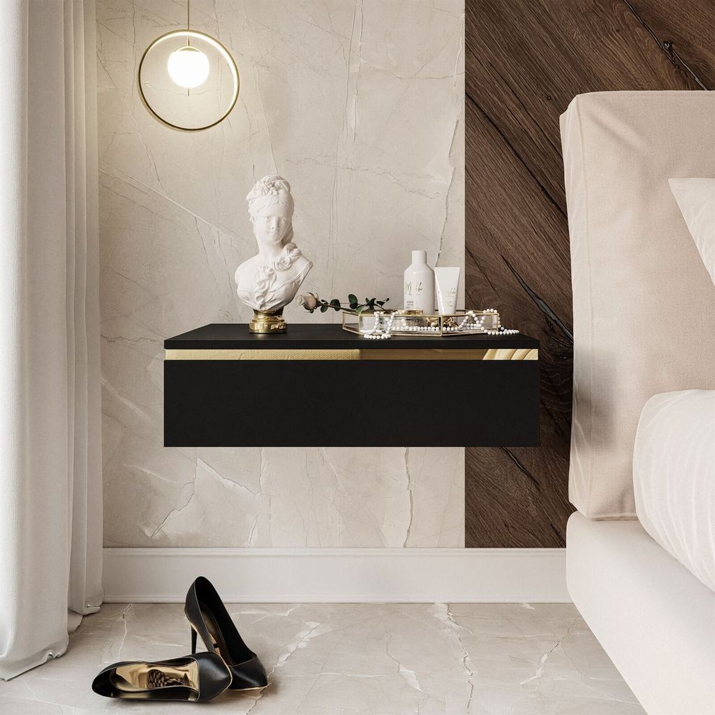 A modern bedroom scene featuring a black floating nightstand with gold accents, a bust sculpture, and toiletries.
