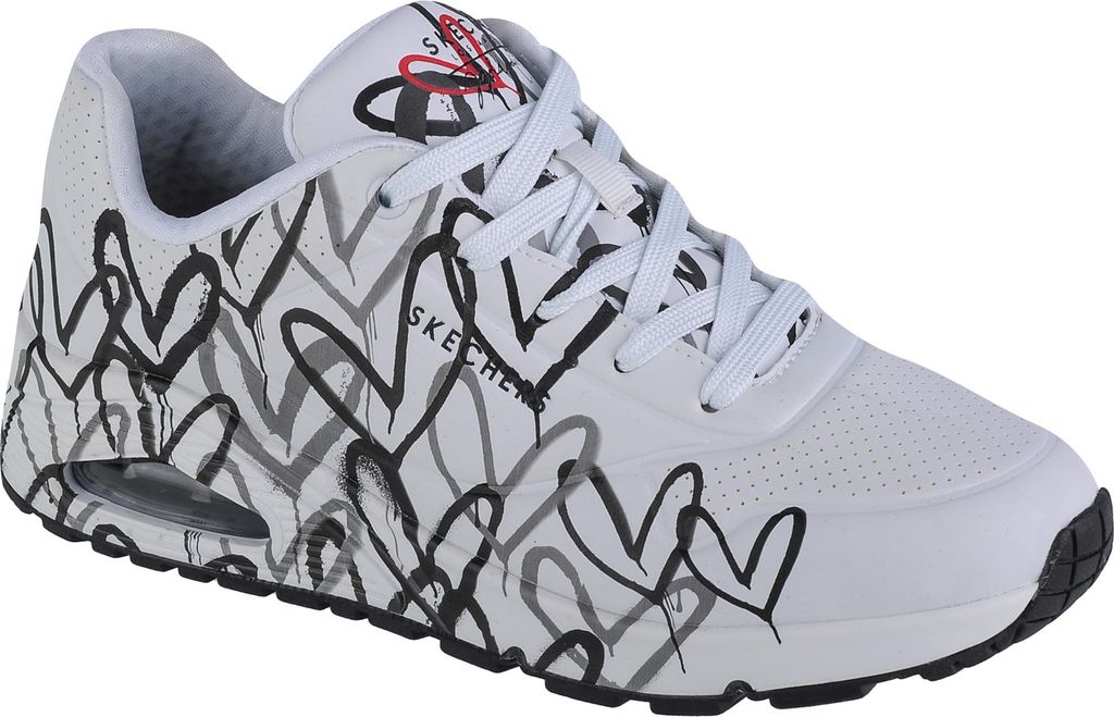 A white SKECHERS sneaker with a black and gray heart pattern.