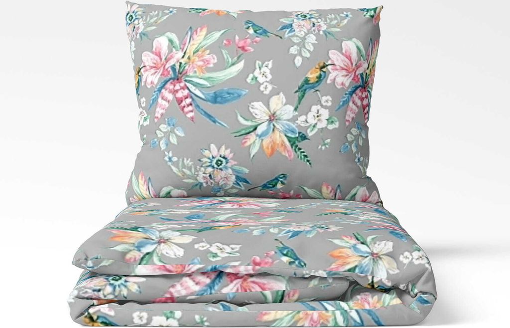 A folded duvet and pillow with a floral and bird pattern on a light gray background.