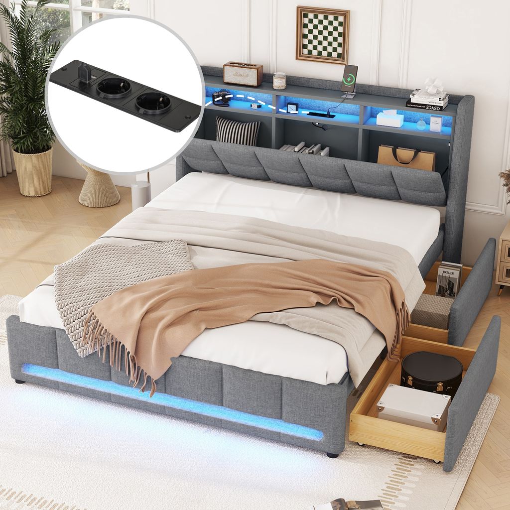 A bedroom scene featuring a grey upholstered bed with storage drawers and a headboard with integrated lighting and shelving. The bed is made up with bedding and throws.