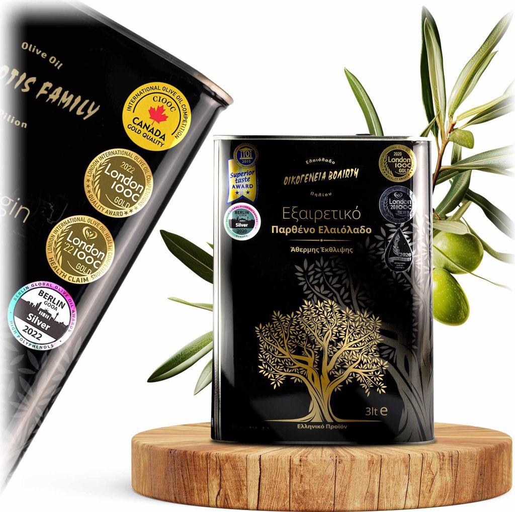 A black olive oil tin with gold accents and awards displayed on a wooden stand, with an olive branch in the background.