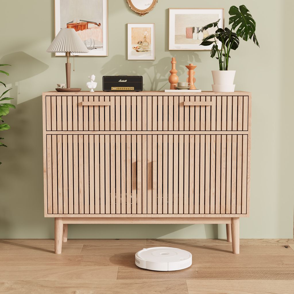 A wooden sideboard with drawers and cabinets is shown in a room with artwork and a plant.