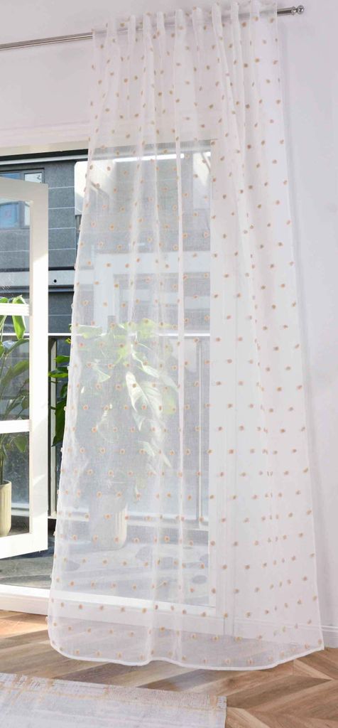 A sheer curtain with small dots hanging in front of a window.