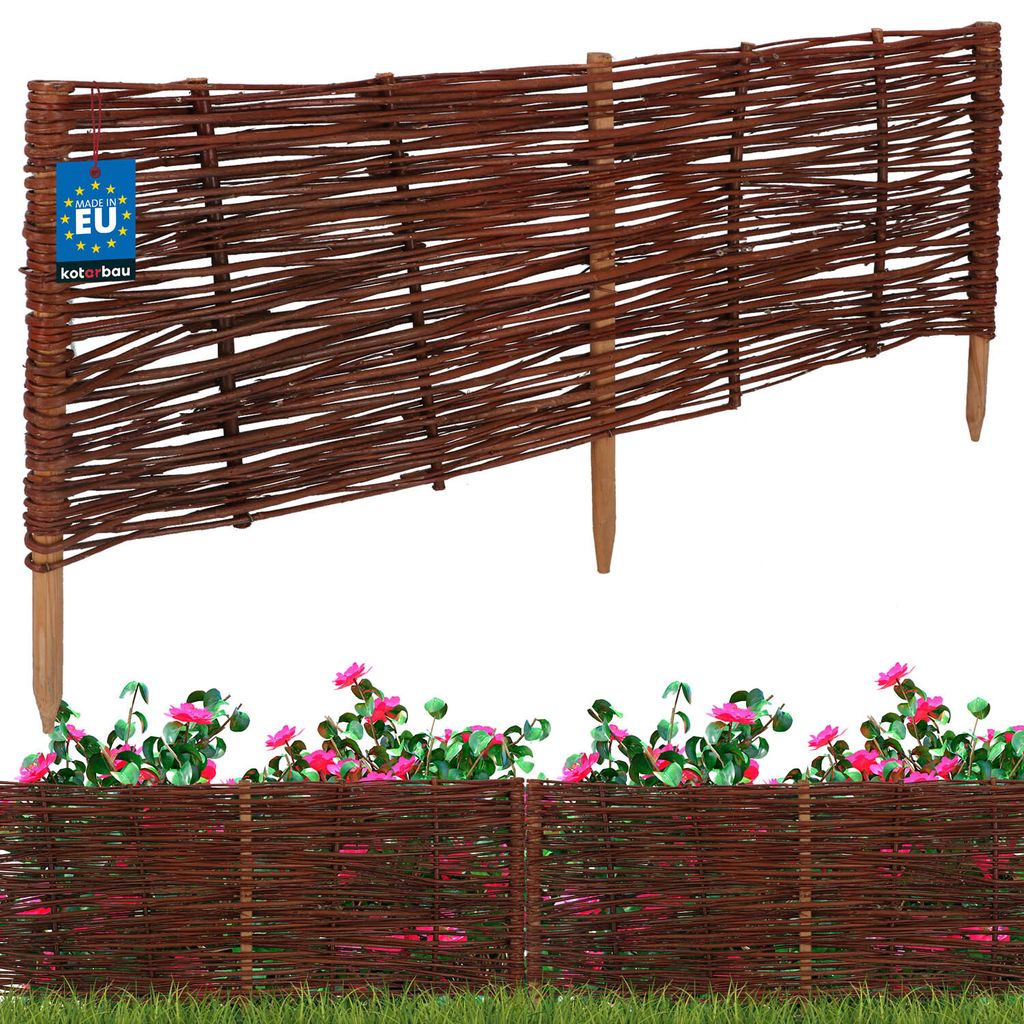 A woven willow garden border fence with pink flowers and green grass.