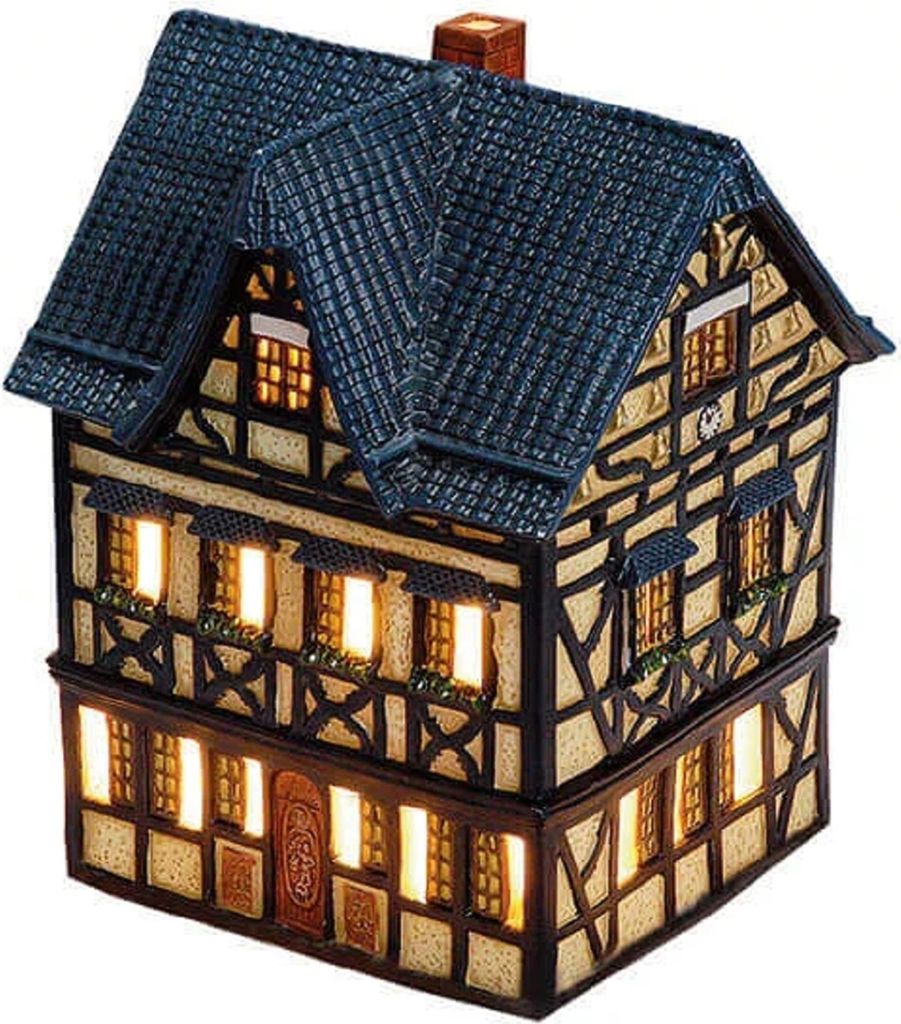A miniature, illuminated house with a dark blue roof and timber-framed walls.