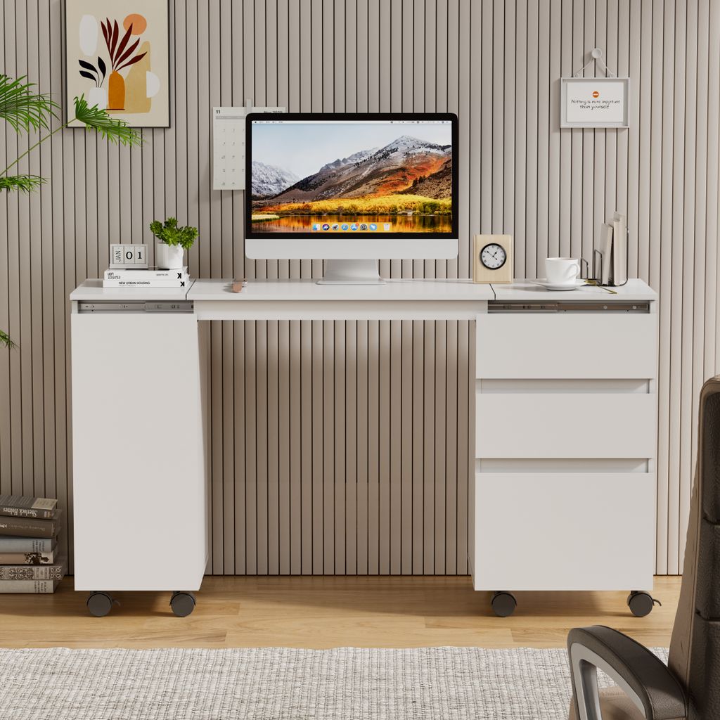A modern white desk with a computer monitor, drawers, and a side cabinet, set against a textured beige wall.