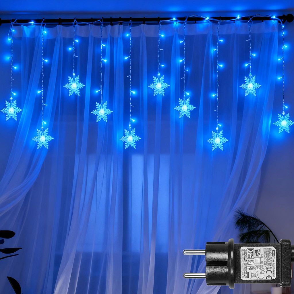 Blue snowflake string lights hanging in front of sheer white curtains.