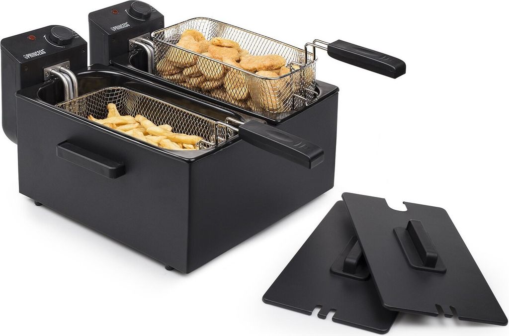 A black double deep fryer with two baskets, one filled with french fries and the other with chicken nuggets. Two black lids are placed in front of the fryer.