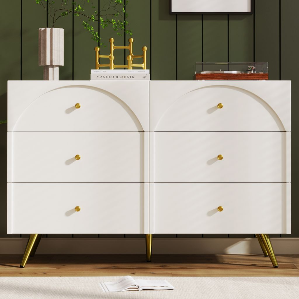 A white dresser with gold legs is shown in a room with green walls.