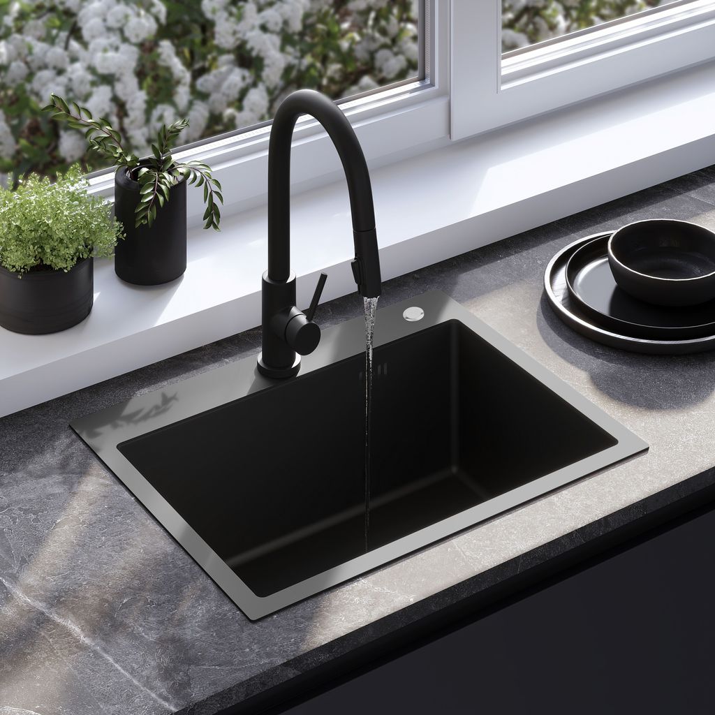 A black kitchen sink with a black faucet is shown with water running into it. There are plants on the windowsill behind the sink and a stack of black plates to the right.