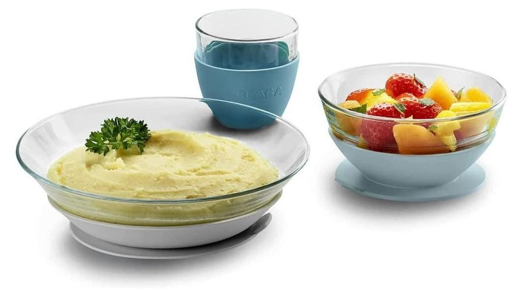 A set of baby dishes including a bowl of mashed food, a bowl of fruit salad, and a cup.