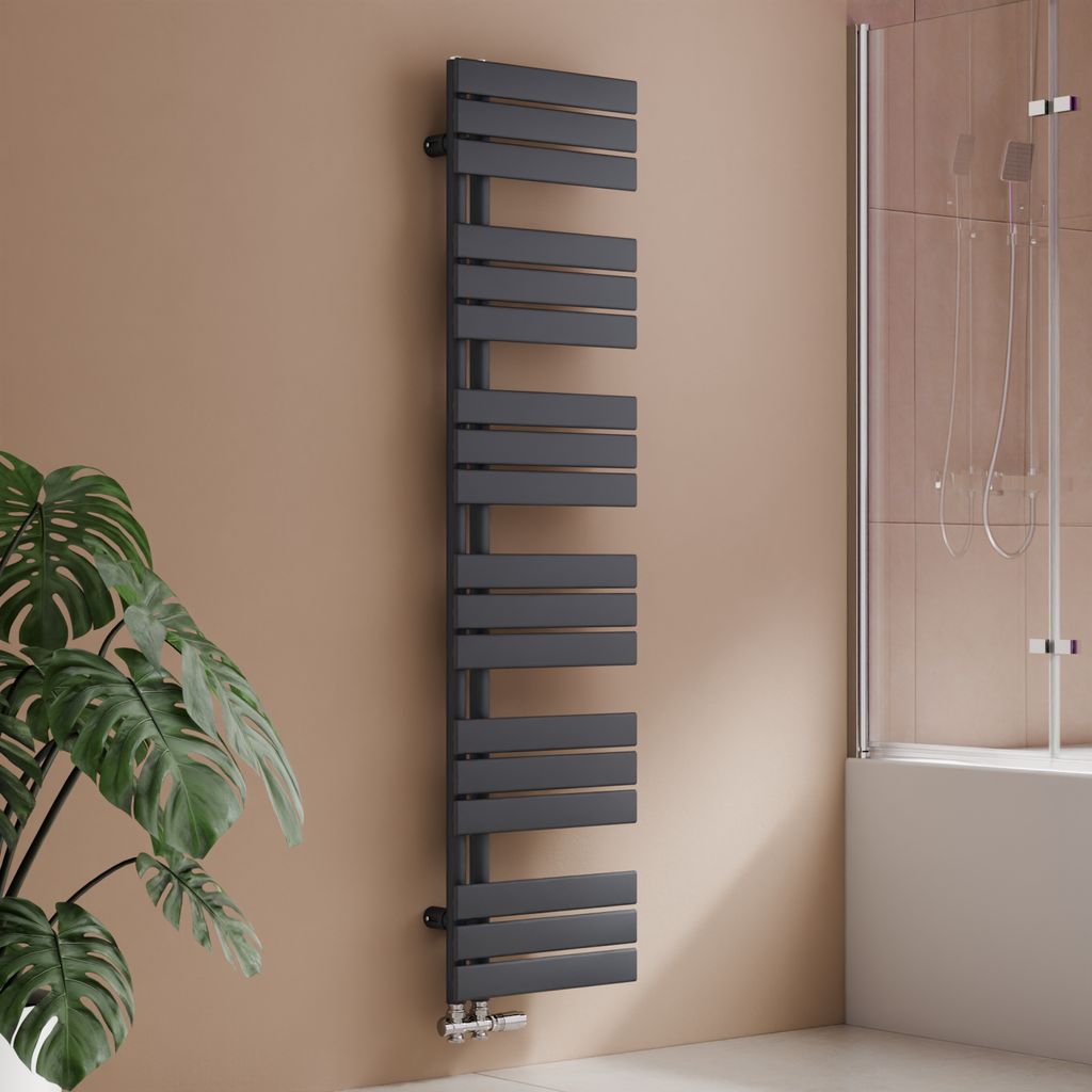 A modern anthracite radiator in a bathroom setting, next to a plant and a shower enclosure.