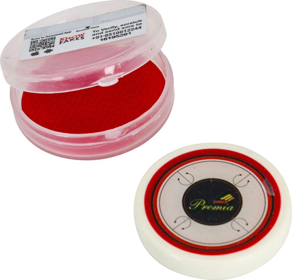 A carrom striker and its container are shown against a white background. The striker is white with red and black accents and the brand name 'Premia' is visible. The container is clear plastic with a red pad inside and has a sticker with text and a QR code.