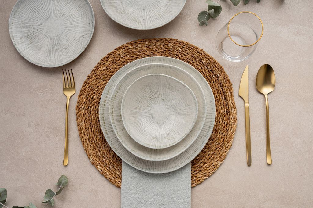 A table setting with plates, cutlery, and a glass.