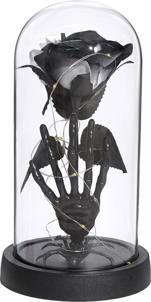 Konservierte schwarze Rosen in einer Glaskuppel, leuchtende ewige Blume in einer Glocke mit Totenkopf-Kürbisstatue für die Dekoration auf dem Kam...