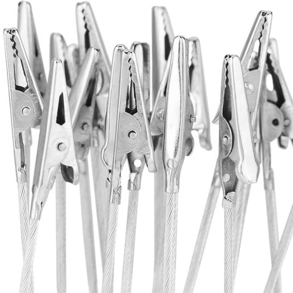 A close-up, tightly cropped shot of multiple silver alligator clips attached to thin wires, against a white background.