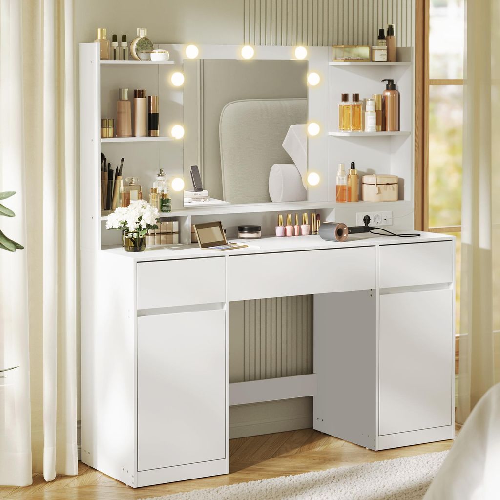 A white vanity table with a mirror and lights, stocked with makeup and accessories, set against a neutral background with curtains.
