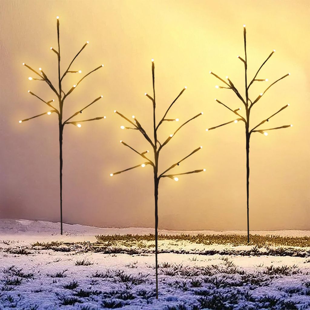 Three decorative LED light branches are placed in a snowy outdoor setting.