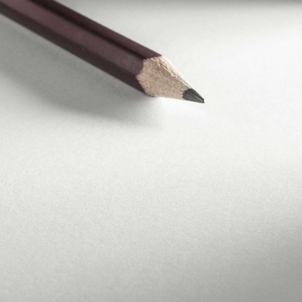 A close-up of a sharpened pencil on a white surface.
