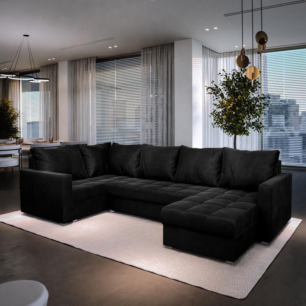 A modern living room with a large black sectional sofa, a rug, and a large window with a city view.