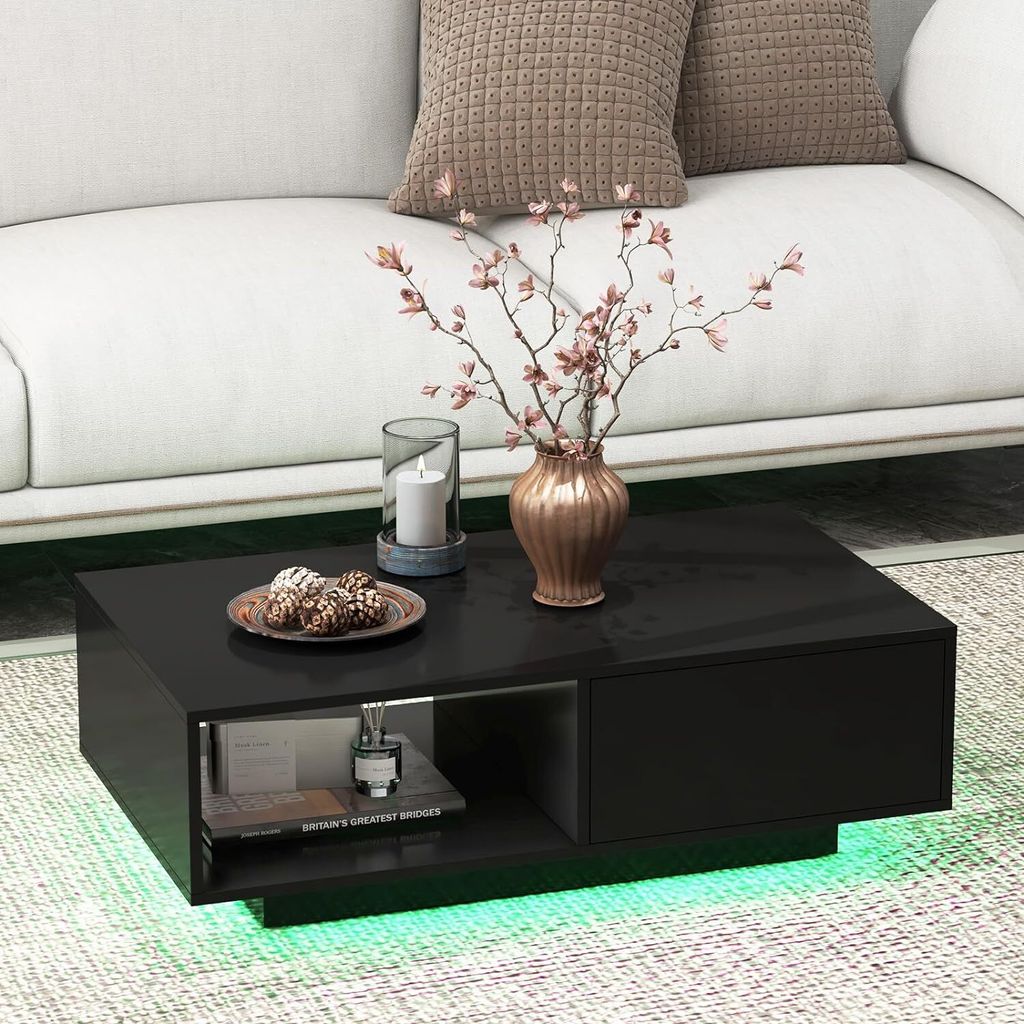 A black coffee table with green LED lighting underneath, placed in front of a white couch.