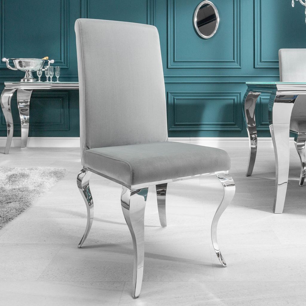 A grey velvet-look dining chair with silver legs is shown in a room with teal walls and a console table.