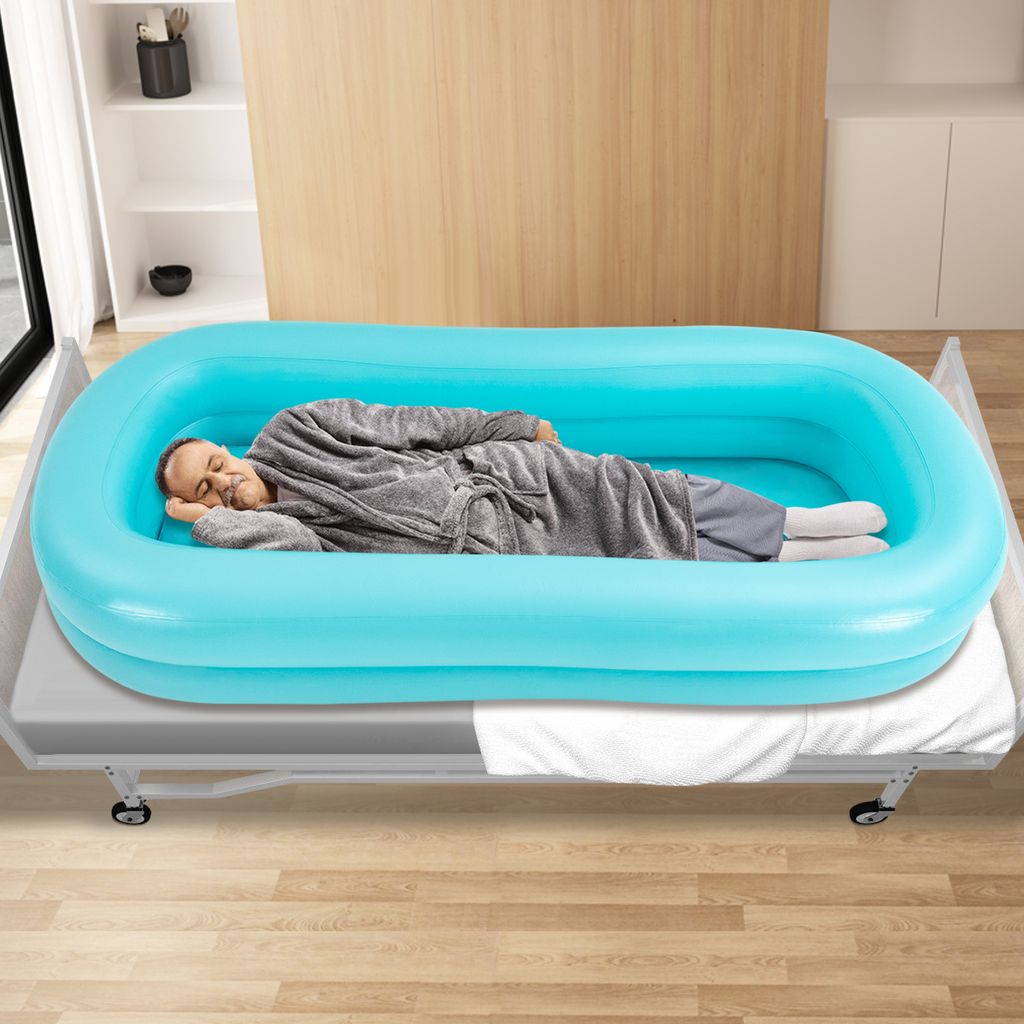 A man is lying in an inflatable bathtub on a bed.
