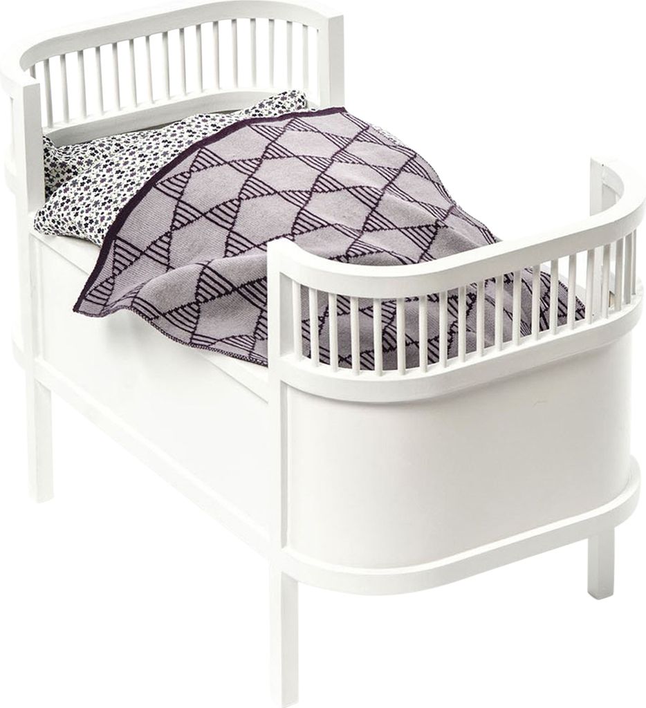 A white wooden doll bed with a patterned pillow and a gray and black patterned blanket.