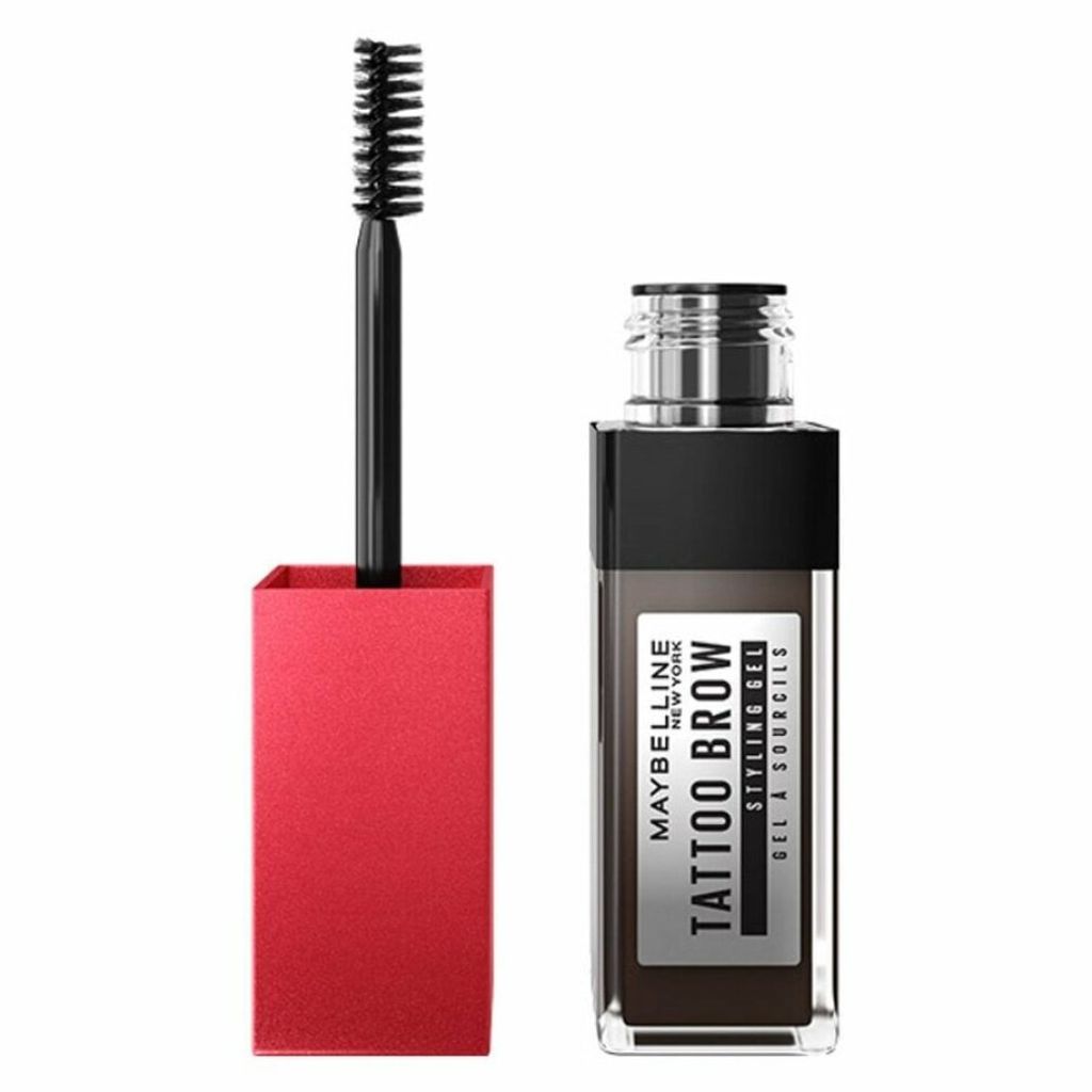 A Maybelline New York Tattoo Brow Styling Gel in medium brown is shown against a white background. The product is displayed with its applicator wand extended.