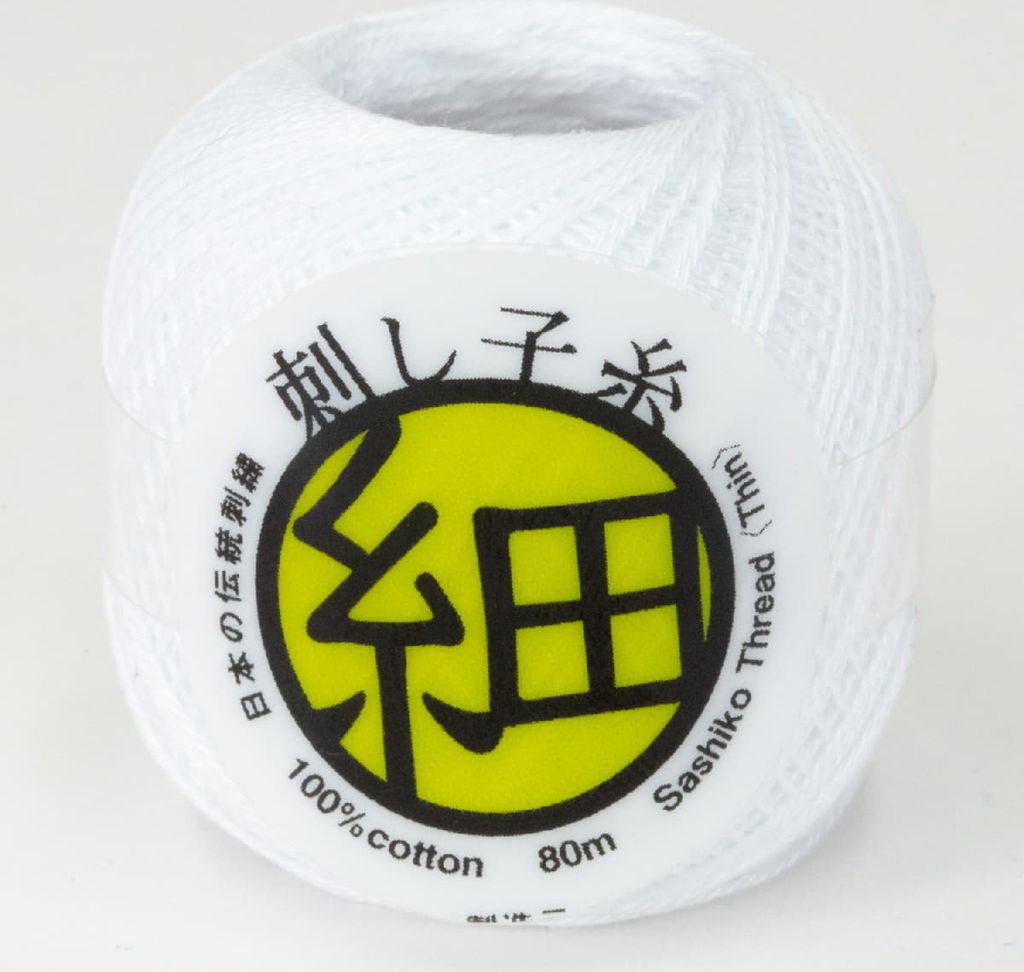 A spool of white Sashiko thread on a plain background.