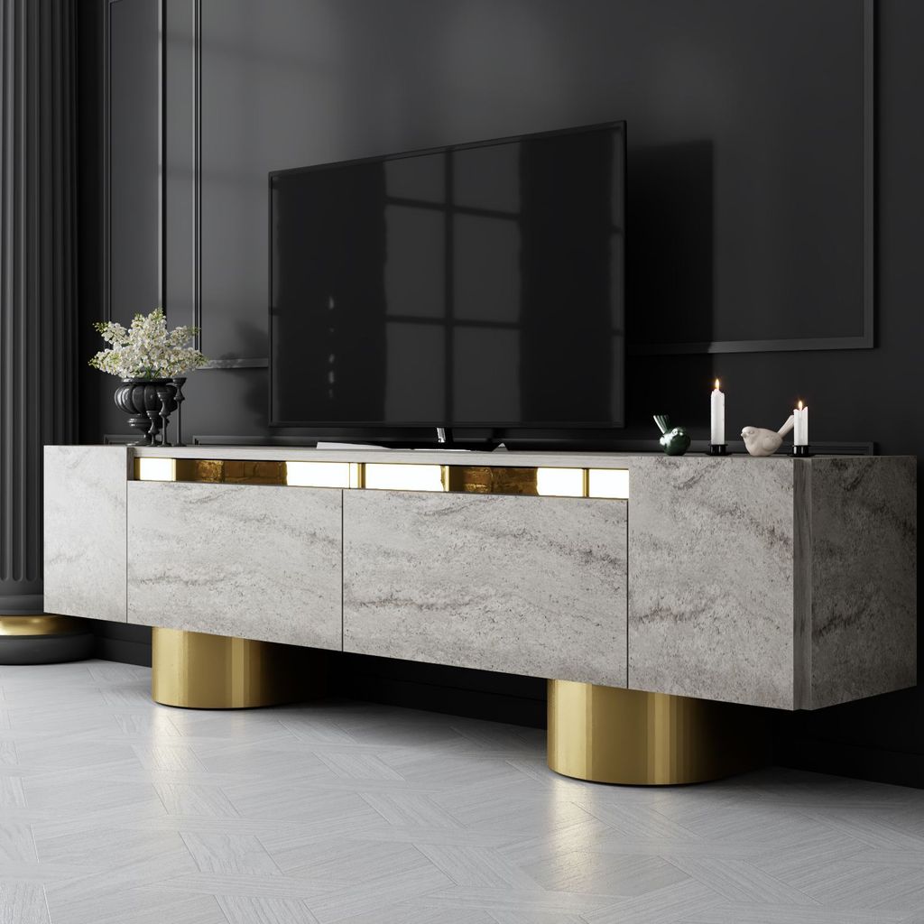 A modern TV stand with a marble-like finish and gold accents, placed in a dimly lit room with a large TV on top.