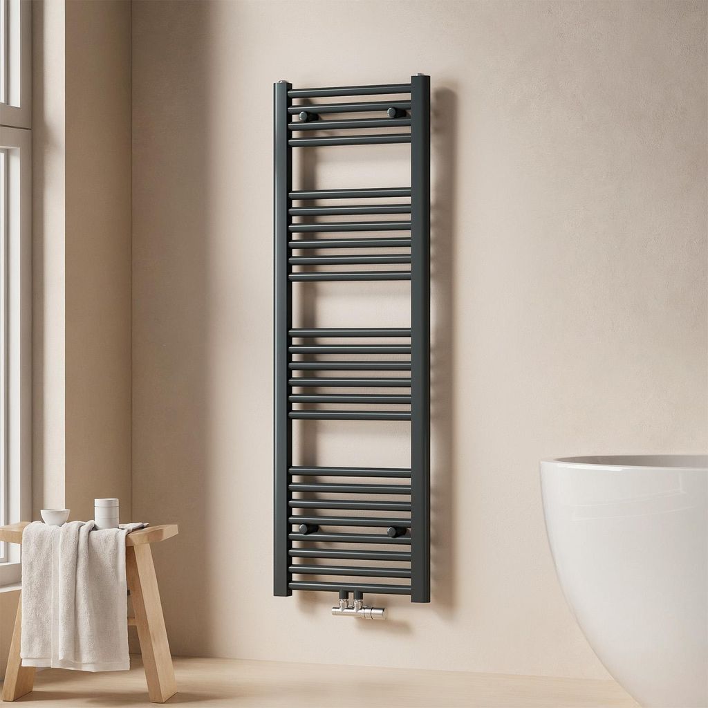 A dark grey towel radiator is mounted on a light beige wall next to a white bathtub. A wooden stool with a folded towel and some small containers is placed to the left of the radiator.