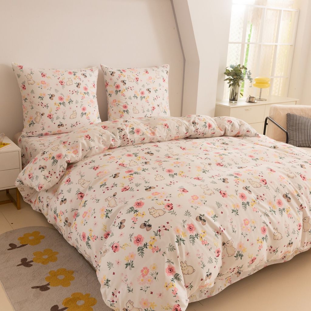 A neatly made bed with a floral and bunny patterned duvet cover and pillows.