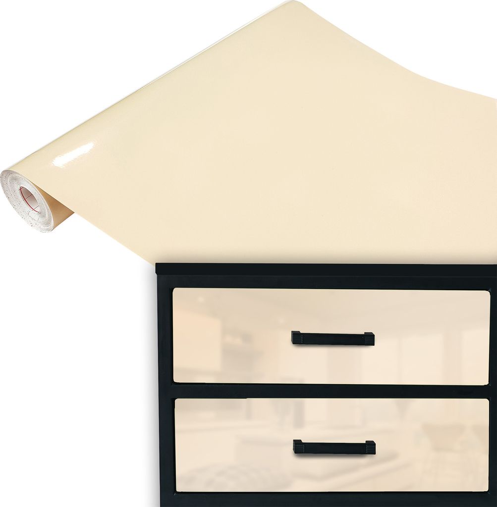 A roll of cream-colored glossy vinyl wrap is unfurled over a black-framed set of two cream-colored drawers with black handles.