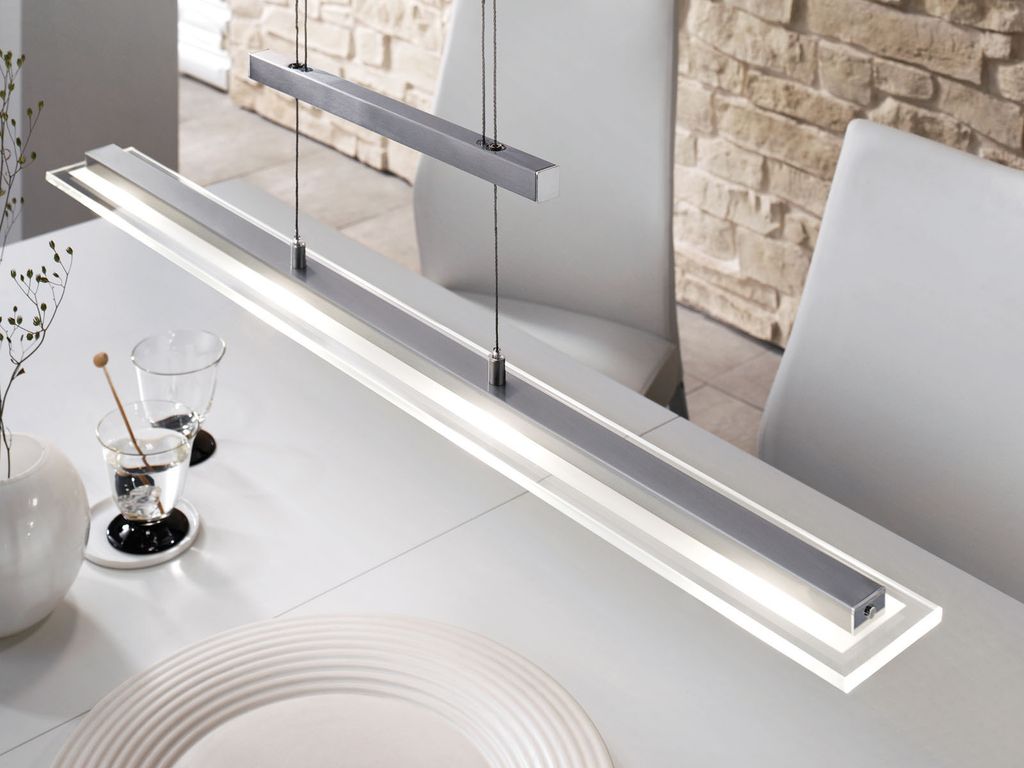 A modern linear pendant light hangs over a white dining table.