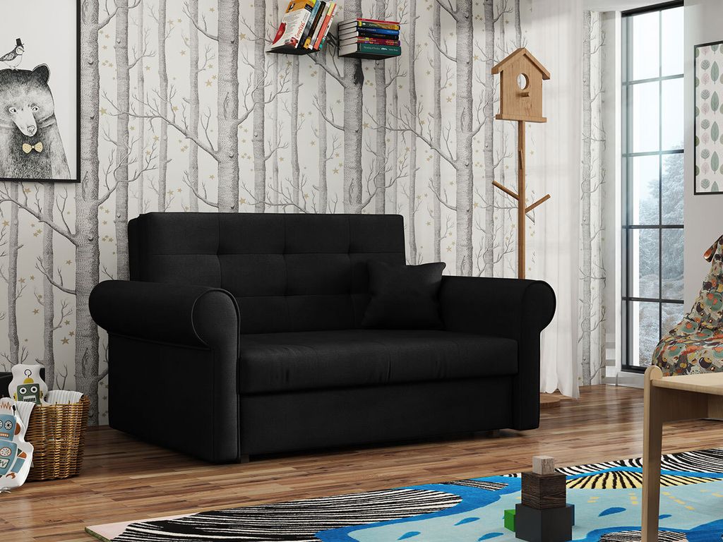A black sofa in a room with patterned wallpaper, a window, and a rug.