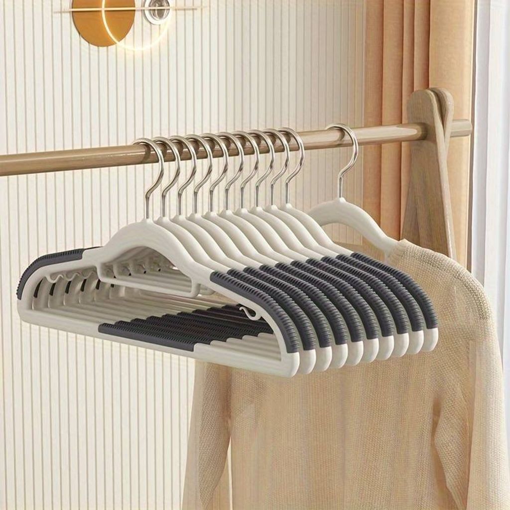 A set of gray, non-slip hangers are neatly arranged on a clothing rack.