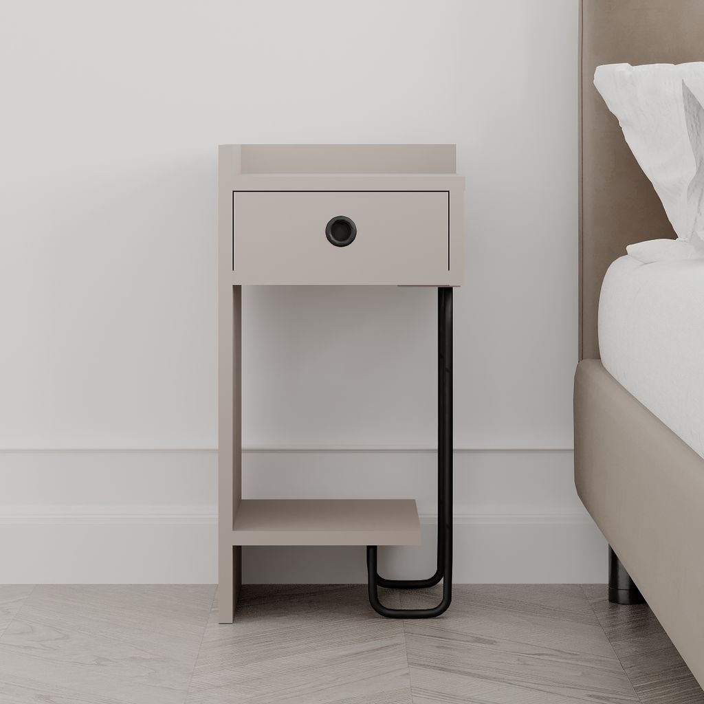 A modern nightstand with a drawer and an open shelf, placed next to a bed in a bedroom setting. The nightstand has a light mocha finish and black metal legs.