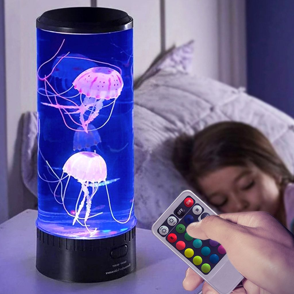 A child is sleeping next to a jellyfish lamp that is lit up with colorful lights.