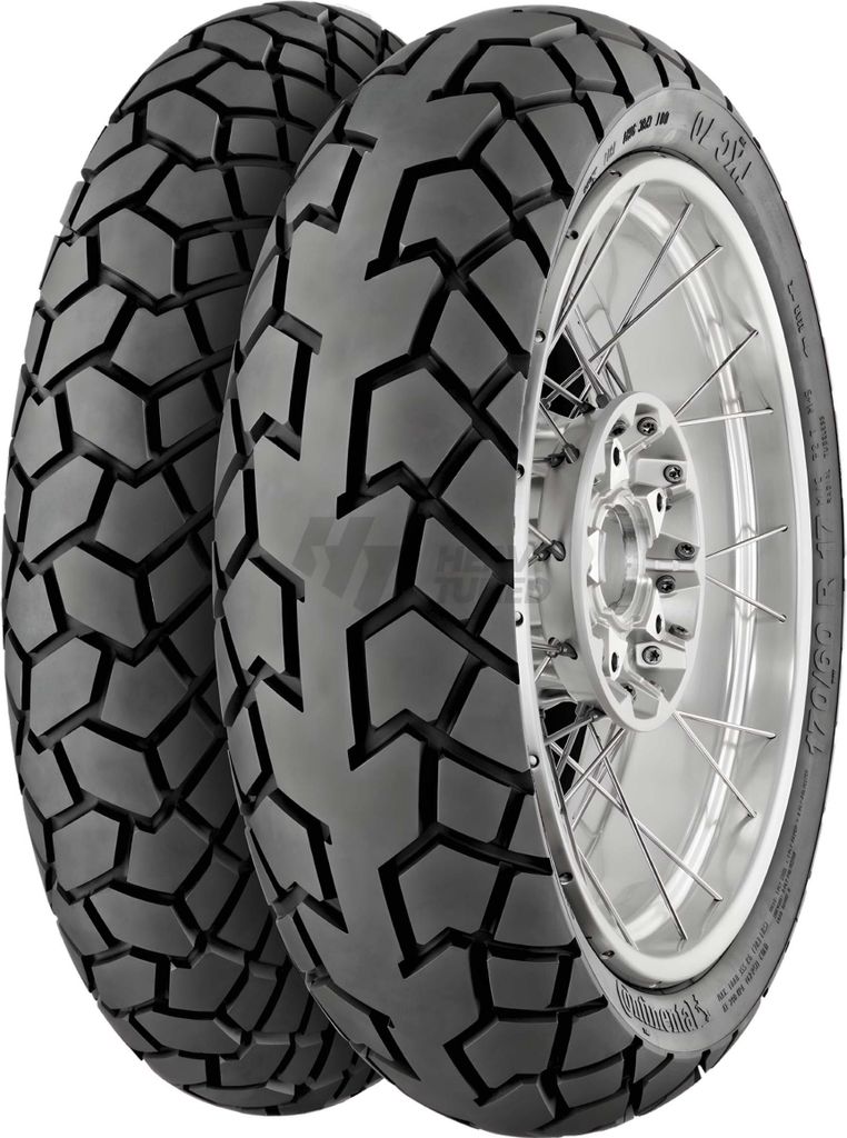 Two motorcycle tires are shown, one in front of the other, with one mounted on a silver rim.