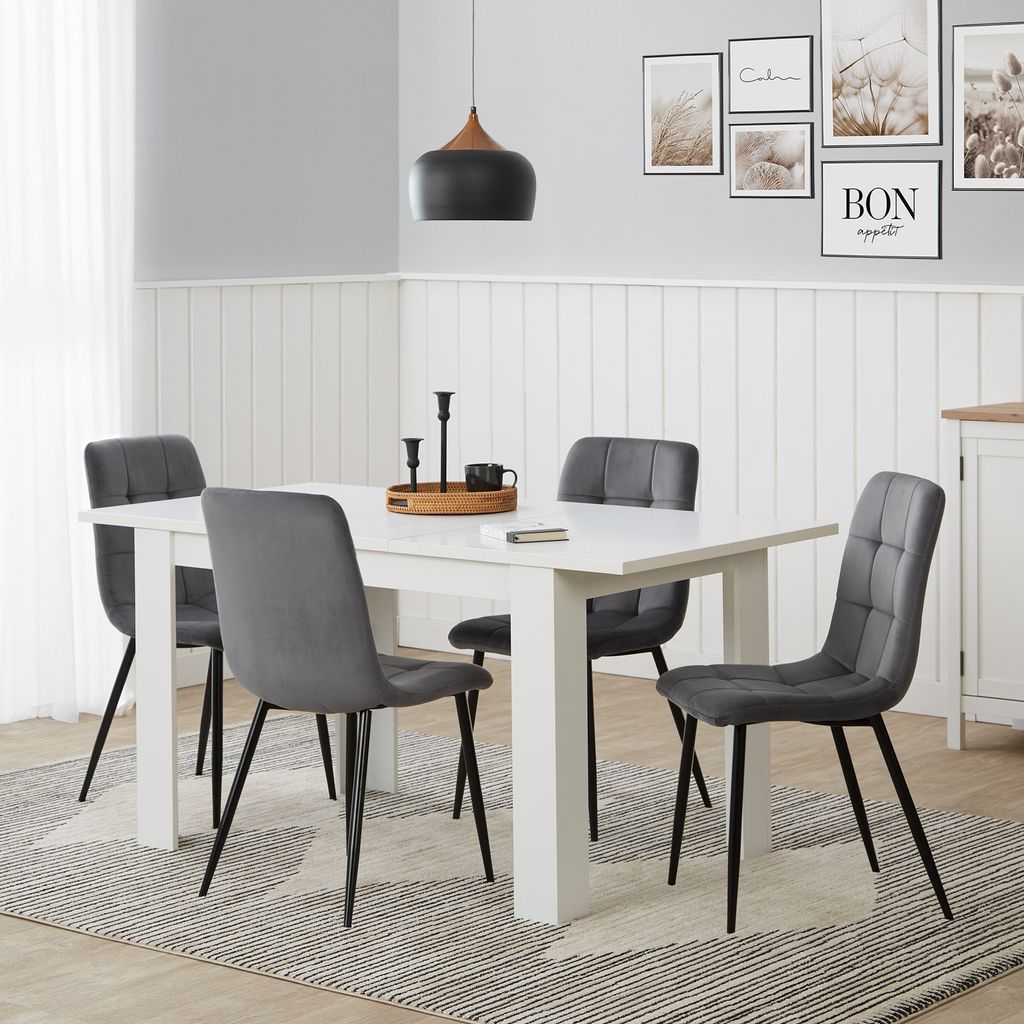 A dining room scene with a white table and four gray chairs.