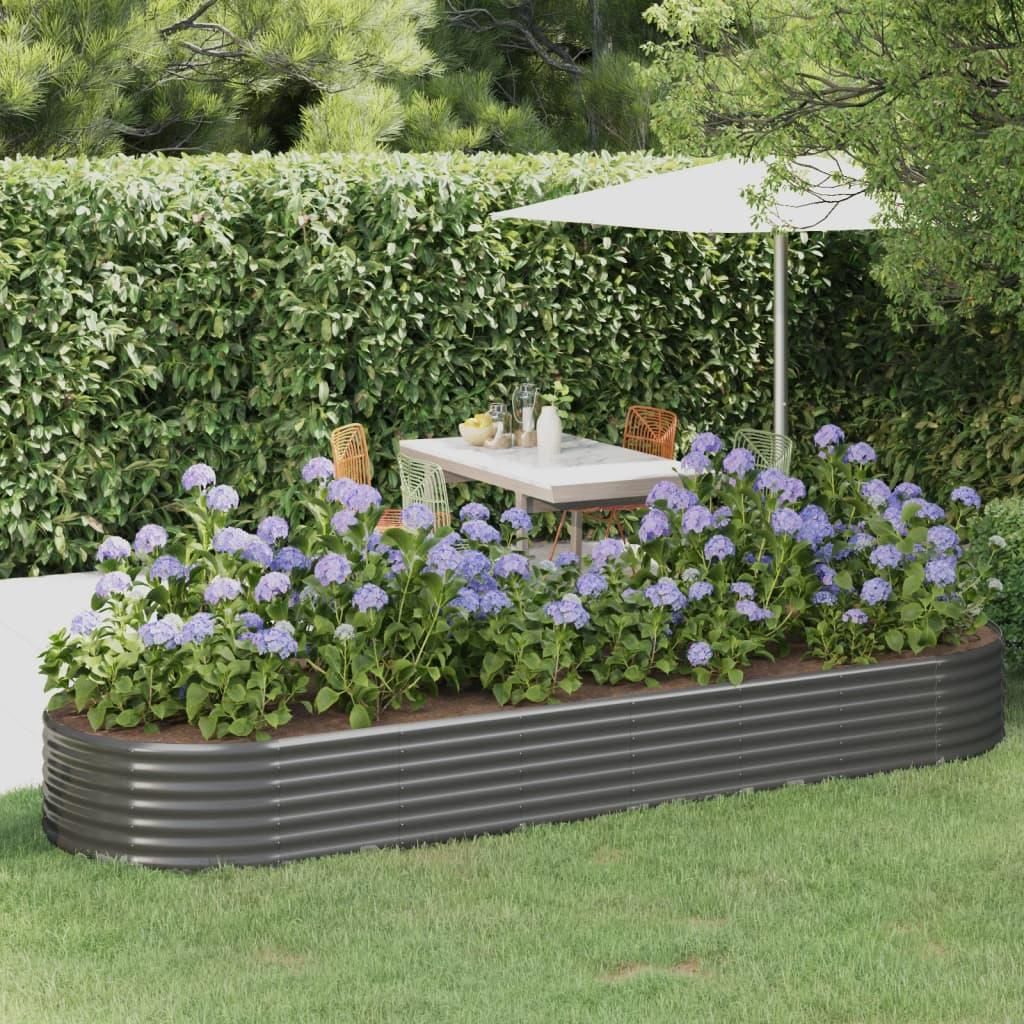 A raised garden bed filled with hydrangeas is set in a garden with a table and chairs under an umbrella in the background.