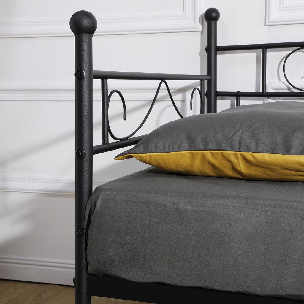 Close-up of a black metal bed frame with bedding and a pillow.