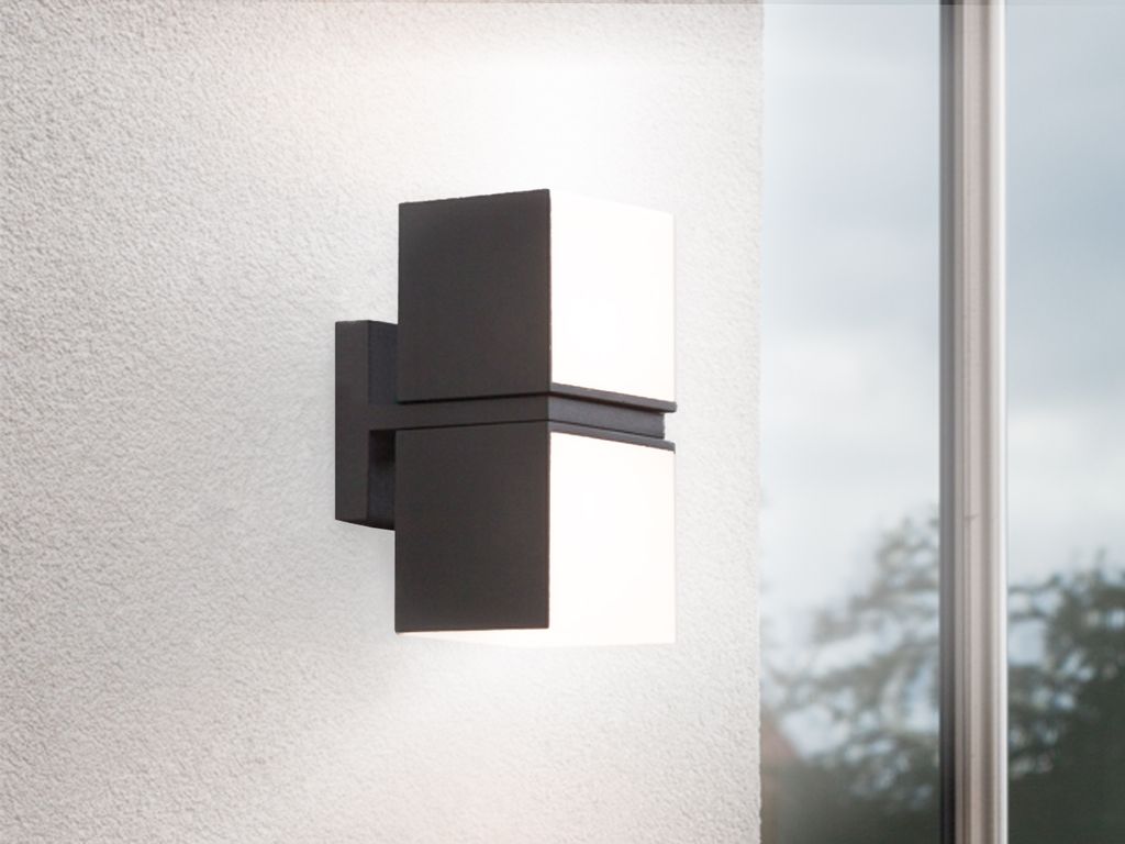 A modern outdoor wall light mounted on a textured white wall, next to a window.
