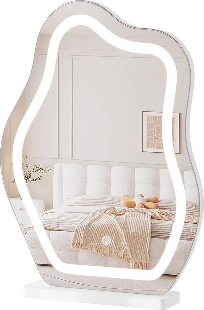 A mirror with integrated LED lighting is displayed on a white stand, reflecting a bedroom scene.