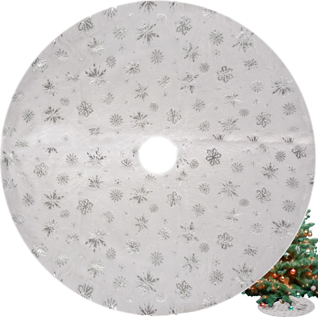 A white circular Christmas tree skirt with silver snowflake patterns is shown, with a portion of a decorated Christmas tree visible in the bottom right corner.