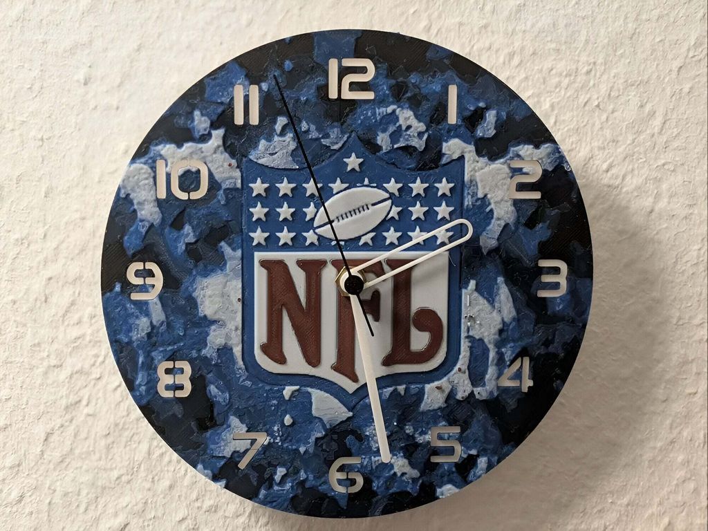 A round clock with the NFL logo in the center, mounted on a textured wall.