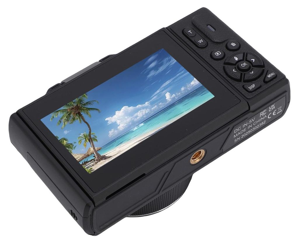 The back of a black digital camera displaying a tropical beach scene on its screen.